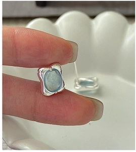 Detail of S925 silver earring with an oval light blue gemstone held by hand