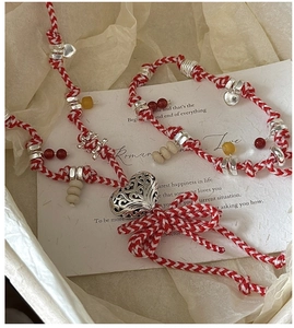 Detail of S925 silver heart pendants on a red and white woven bracelet in a gift box