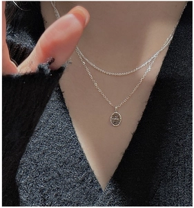 Détail d'un collier double rang en argent S925 avec pendentif ovale sur tricot noir