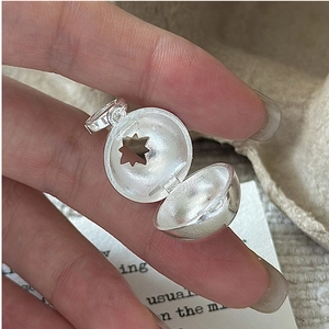 Macro detail showing a spherical S925 silver locket with a hollow star and matte finish
