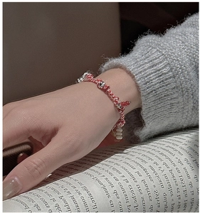 Detail of handcrafted silver bead cord bracelet worn by model on a book background