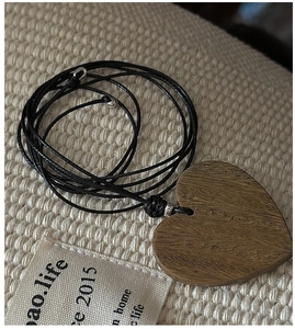 Detailed view of heart-shaped dark wood pendant with natural grain on woven fabric