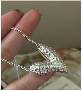Close-up of S925 sterling silver heart pendant with shimmering CNC faceted texture