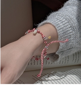 Detail of red and white braided S925 silver bracelet with beads on a model's wrist