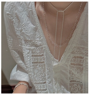 Detail view of S925 sterling silver long heart necklace worn on a white lace V-neck blouse