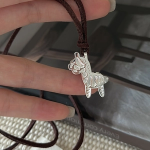 Minimalist S925 silver zebra pendant necklace with brown woven cord on vintage background
