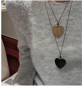 Detail of heart pendants with wood grain texture and black resin on a minimalist cord
