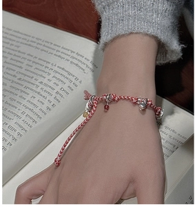 Detail of S925 silver heart charm on red and white braided rope bracelet on wrist