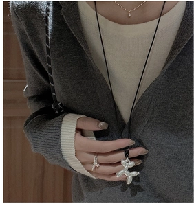 Détail du collier chien ballon en argent et bague étincelante sur un cardigan en maille