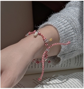 Detail of S925 silver woven bracelet with bone charm worn over a gray knit cuff