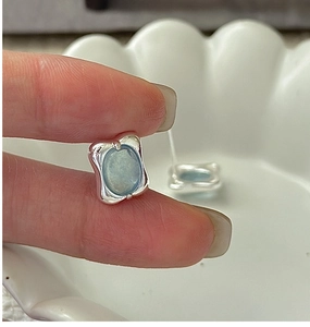 Macro shot of S925 sterling silver aquamarine earrings with irregular wavy metal frames