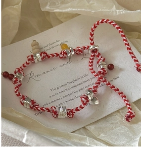 Detail of red and white braided S925 silver bracelet with colorful beads on a gift card
