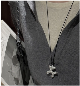 Détail du collier avec pendentif chien ballon en argent porté avec un sweat à capuche