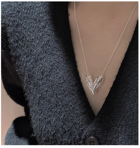 Close-up of S925 sterling silver heart pendant with woven texture on black knitwear