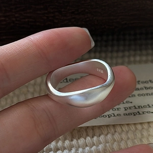 S925 sterling silver ring with irregular wave design and matte finish held by hand