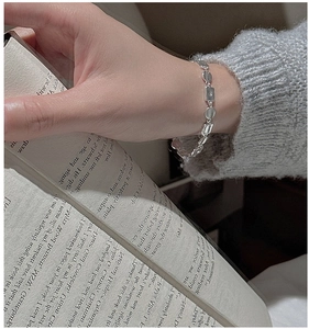 Close-up of minimalist S925 sterling silver geometric link bracelet on model's wrist
