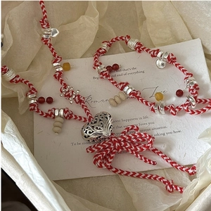 Close-up of S925 silver woven heart bracelet with red beads on a romantic gift card