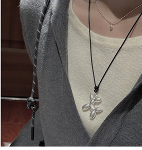 Détail d'un collier avec pendentif chien ballon argenté porté sur un cordon noir discret