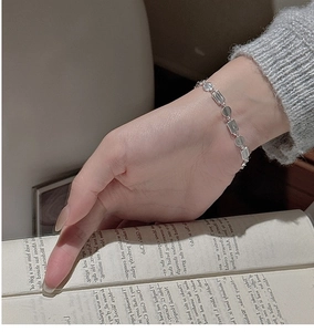 Detail of minimalist S925 sterling silver matte link bracelet worn on wrist over a book