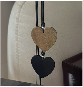 Detail of wooden and black matte heart pendants on a long necklace with textured grain