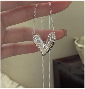 Detailed close-up of a faceted S925 sterling silver heart pendant on a thin link chain