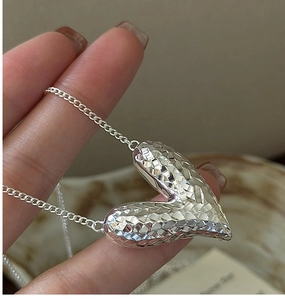 Detail of S925 sterling silver heart pendant with CNC diamond-cut texture on a thin chain