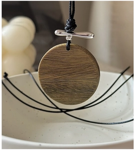 Détail du pendentif rond en bois veiné naturel sur un collier en argent S925