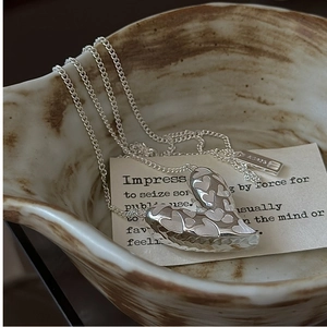 Close-up of S925 sterling silver heart pendant with engraved texture on ceramic bowl