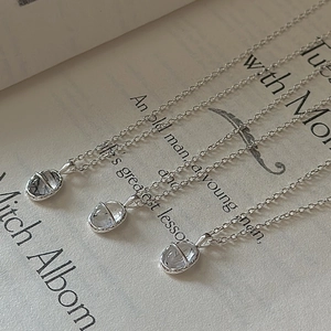 Trois colliers en argent S925 avec pendentifs ovales en quartz rutilé posés sur un livre