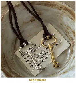 Detailed view of vintage gold and silver key pendants on dark brown leather cords