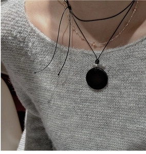 Détail d'un collier en argent S925 avec pendentif grain de bois noir sur tricot gris
