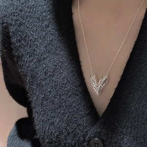S925 sterling silver heart necklace with textured CNC finish on a grey fabric background