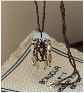 Macro detail of Bohemian pendant necklace with brown seed beads and silver tassels