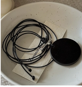 Gros plan d'un collier pendentif en argent à texture boisée dans un bol en céramique