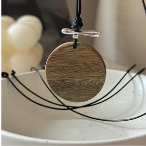 Détail du collier à pendentif rond en bois avec fermoir en argent et cordelette noire