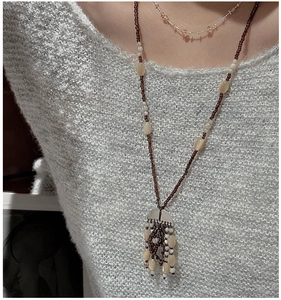 Detail view of retro beaded long necklace with tassels on a grey knit sweater