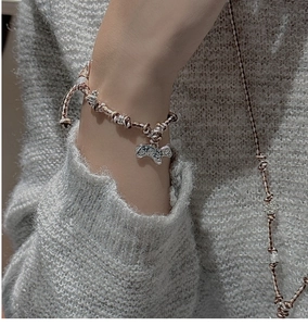 Gros plan d'un charm cheval en argent S925 sur bracelet tressé marron sur manche grise