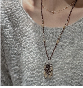 Detail of layered 925 silver retro necklace with amber beads on grey knit sweater