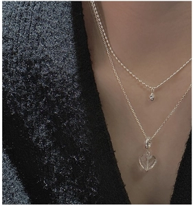 Detail of layered S925 silver necklaces with heart crystal and teardrop pendants