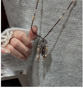 Detail of beaded brown necklace and matching flower ring on a grey knit sweater