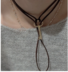 Detail of vintage gold key pendant on dark brown velvet cord over a grey sweater