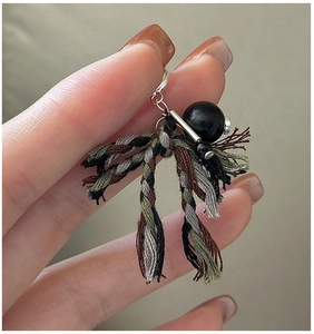 Macro shot of handmade woven fabric tassel pendant with retro beads and silver hardware