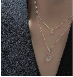 Detail of S925 silver layered necklace with heart crystal and bean pendant on model