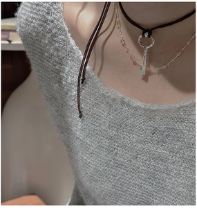 Detail view of layered S925 silver key necklace and beaded chain on grey knit sweater