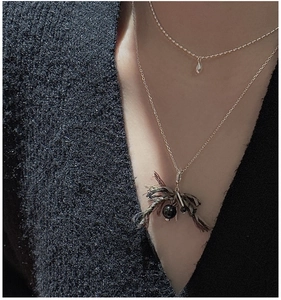 Detail of S925 sterling silver layered necklace with black bead and vintage tassel on a model
