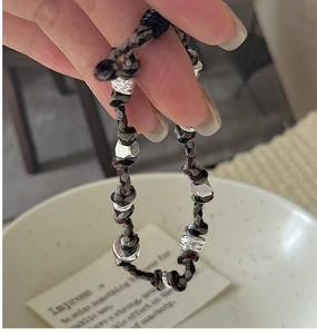 Dettaglio del bracciale in corda intrecciata a mano con perle argentate stile retrò
