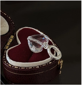 Macro detail of heart-cut crystal pendant on S925 silver bail inside a red gift box