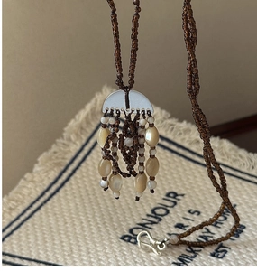 Detail of retro beaded necklace with brown tassels and silver semi-circle pendant