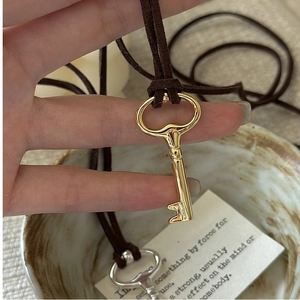 Detail of vintage silver key pendant necklace with dark brown suede cord strap