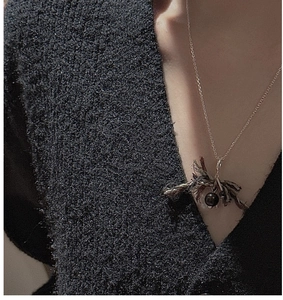 Macro detail of S925 silver O-chain necklace with bohemian brown woven fabric tassel pendant